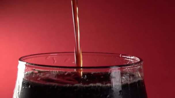 Movimento lento Close-Up Cola despeje em vidro em um fundo vermelho — Vídeo de Stock