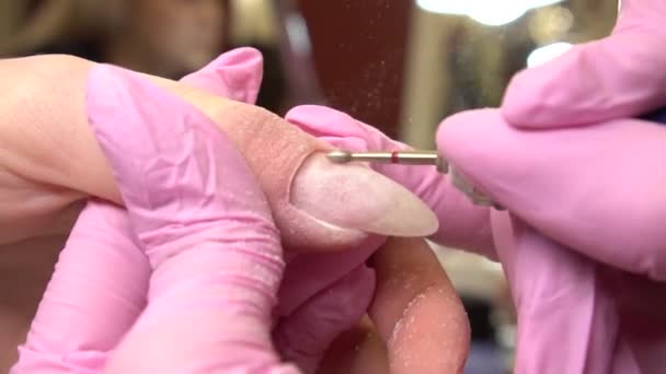 Un primo piano di manicure hardware in un salone di bellezza. Manicurista sta applicando la lima elettrica trapano per cuticole assetto sulle dita femminili — Video Stock