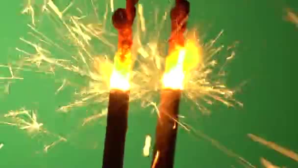 Een sparkler wordt aangestoken omhoog en branden tegen groene achtergrond — Stockvideo