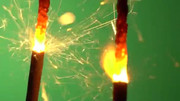 Een sparkler wordt aangestoken omhoog en branden tegen groene achtergrond — Stockvideo