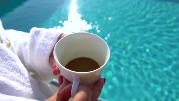 Kvinnan på morgonen dricker kaffe på hotellets pool — Stockvideo