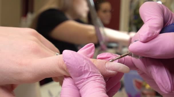 Procedimiento de manicura de cerca. Manicura de niña con guantes médicos rosas y un dispositivo especial en sus manos. Cuidado de las uñas. Salón de belleza. Movimiento lento — Vídeo de stock