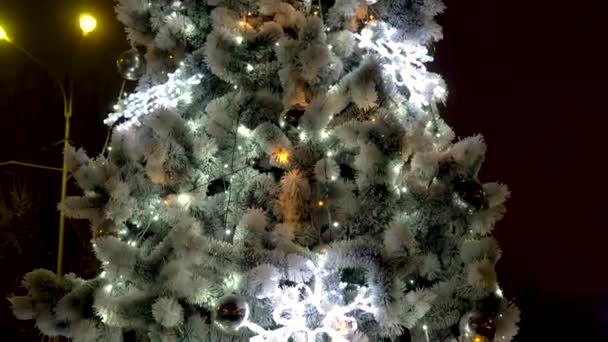 Closeup vídeo de luzes led coloridas brilhantes e piscando na árvore de Natal contra a lareira em chamas à noite. Tiro perfeito para celebrações de inverno e feriados — Vídeo de Stock