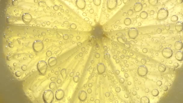 Su kabarcıklarındaki limon diliminin makro görüntüsü. — Stok video