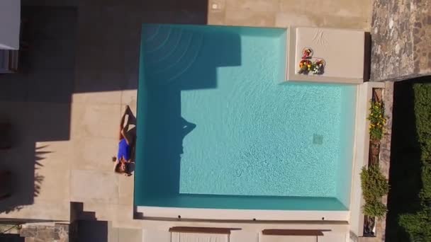 Aéreo - bela jovem mulher tomando banho de sol na toalha perto da piscina em vermelho — Vídeo de Stock