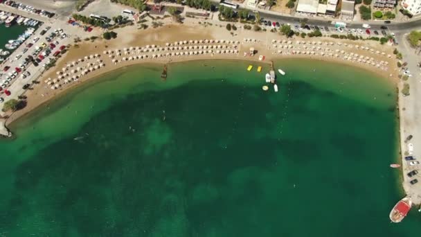 在蔚蓝沙滩上飞行的高空鸟瞰，人们在毛巾上晒日光浴，在绿水中嬉戏. — 图库视频影像