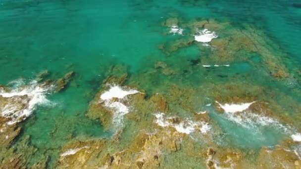 石とターコイズブルーの海の波のある崖の海岸線の空中写真。垂直ドローン — ストック動画