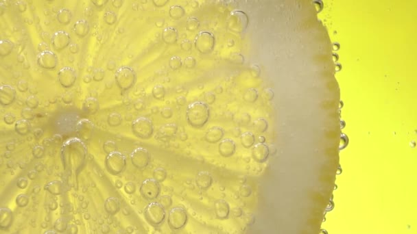 Αργή κίνηση φρέσκο λεμόνι σε σόδα νερό που καλύπτεται με φυσαλίδες — Αρχείο Βίντεο