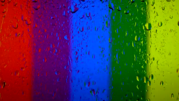 Muitas gotas de água no vidro da janela durante a chuva forte. Arco-íris a bandeira do arco-íris, bandeira do orgulho de Lgbt ou gay — Vídeo de Stock