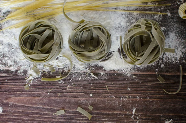 在铺有面粉的木桌上的未煮熟的意大利面 — 图库照片