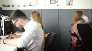 Meşgul tasarım ofis masaları işçi ile geniş açı bakış. 20'li yaşlarda 4 k.