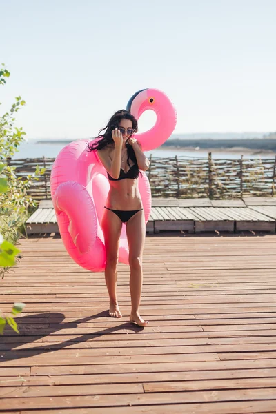 振りかけたピンク インフレータブル フラミンゴ浮動小数点数を保持している美しい女性 — ストック写真