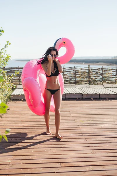 Mooie vrouw met bestrooid roze opblaasbare flamingo float — Stockfoto