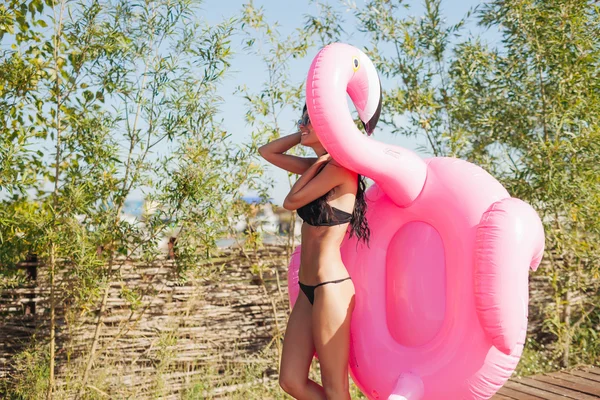 Mooie vrouw met bestrooid roze opblaasbare flamingo float — Stockfoto