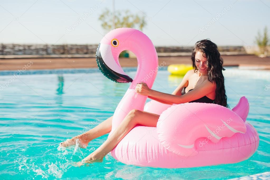 girl sits on inflatable mattress flamingo