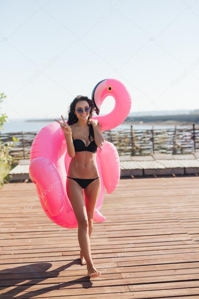 beautiful woman holding sprinkled pink inflatable flamingo float 