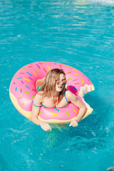 Chica joven en rociado donut flotar en la piscina — Foto de Stock