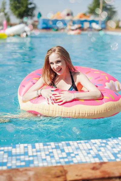 Chica joven en rociado donut flotar en la piscina — Foto de Stock