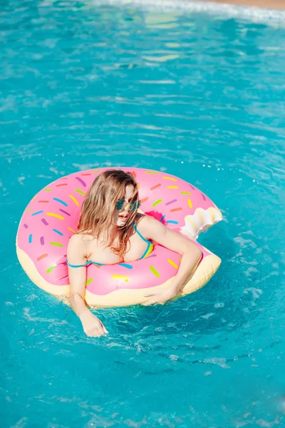 Chica joven en rociado donut flotar en la piscina —  Fotos de Stock