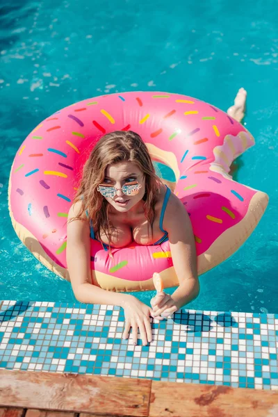 Fiatal lány porcukros fánk úszó medence — Stock Fotó