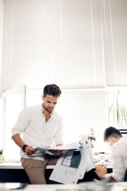 Genç adam dergi okuyor.