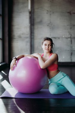 spor salonunda egzersiz topu ile gülümseyen kadın