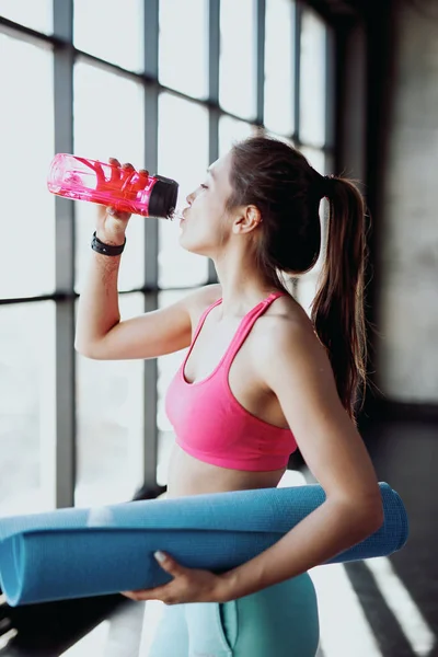 Молода атлетична жінка п'є воду — стокове фото