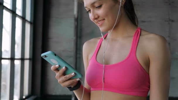 Mujer usando smartphone en gimnasio — Vídeo de stock