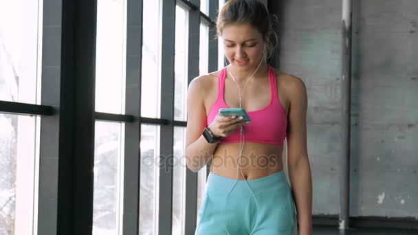 Frau nutzt Smartphone im Fitnessstudio — Stockvideo
