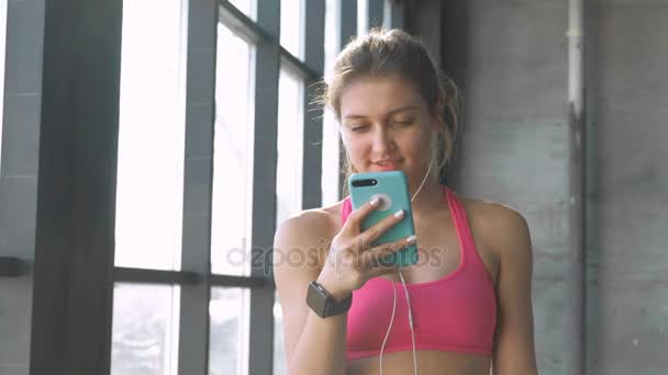 Mujer usando smartphone en gimnasio — Vídeos de Stock