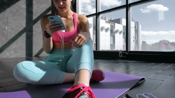 Frau nutzt Smartphone im Fitnessstudio — Stockvideo