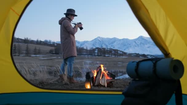 Homem novo que tira uma foto com DSLR na manhã calma do verão após a noite na barraca vermelha 20s 4k — Vídeo de Stock