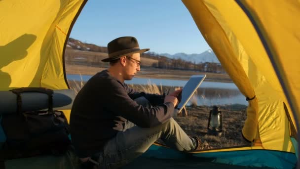 Smiling young man tourist using smartphone sitting in touristic tent at the beach 20s 4k — Stock Video