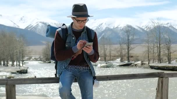 Młody człowiek podróżnik z plecakiem, wyświetlanie map w telefonach komórkowych relaksujący odkryty na background.20s 4k — Wideo stockowe