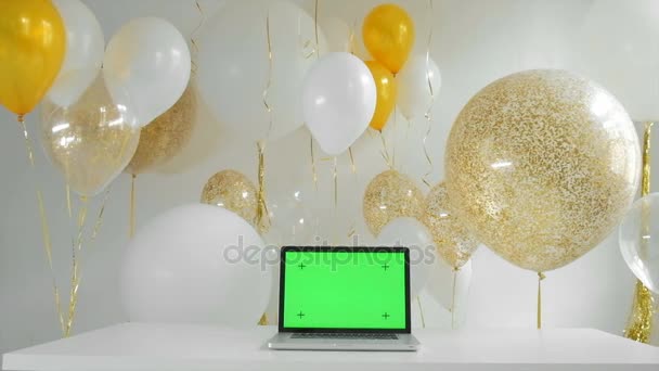 Laptop met geïsoleerde groen scherm. Gouden en zilveren ballonnen achtergrond. Nieuwjaar concept 1080p fullhd — Stockvideo