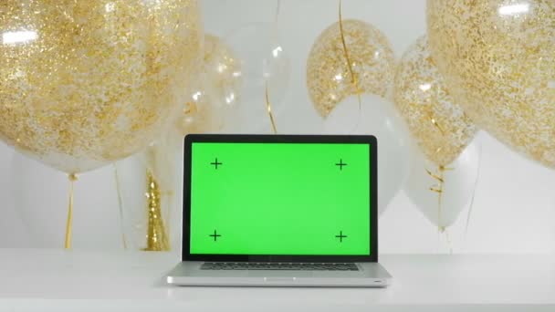 Computer portatile con schermo verde isolato.Oro e argento palloncini sfondo. Nuovo concetto di anno 1080p fullHD — Video Stock