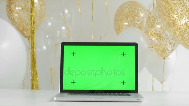 Computer portatile con schermo verde isolato.Oro e argento palloncini sfondo. Concetto di Capodanno. 1080p fullHD — Video Stock