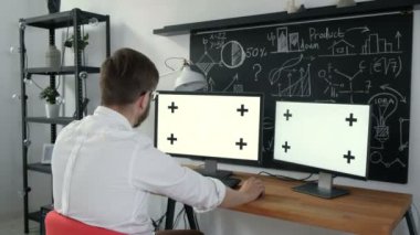 İş bağlantıları çok sayı yeşil ekran. İki bilgisayar ve tüm yeşil ekran ile bir tablet ile çalışan adam. 20'li yaşlarda 4 k