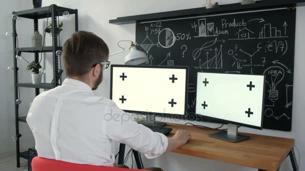 Gros plan d'un homme assis à son bureau avec PC écran vert sur la table. En arrière-plan Bureau flou et lumineux où les gens passent par la routine de bureau. 20s 4k . — Video