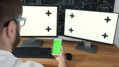 İş bağlantıları çok sayı yeşil ekran. İki bilgisayar ve tüm yeşil ekran ile bir tablet ile çalışan adam. 20'li yaşlarda 4 k