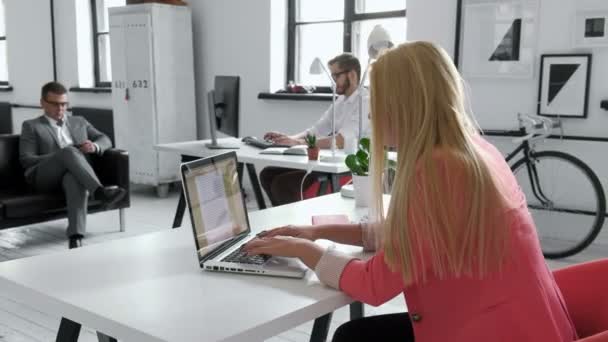 Joven mujer de negocios que trabaja en el escritorio compartido en la oficina de arranque hipster de moda utilizando big data en el ordenador portátil 20s 4k — Vídeo de stock