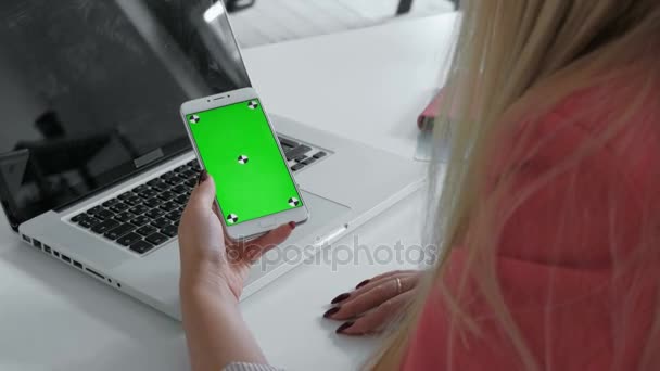 Handen boven weergave. Vrouw met behulp van haar smartphone met groen scherm in tabel, nieuws, foto's te scrollen. Office Bureau achtergrond. 20s 4 k — Stockvideo