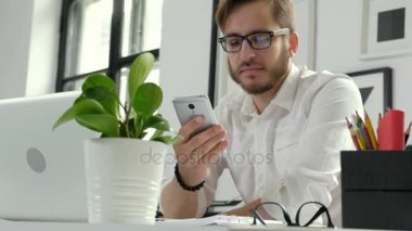Onun akıllı telefon ekranına bakarak ve onun el 20s 4 k bir kalem tutan uzun sakallı yeniyetme yakın çekim