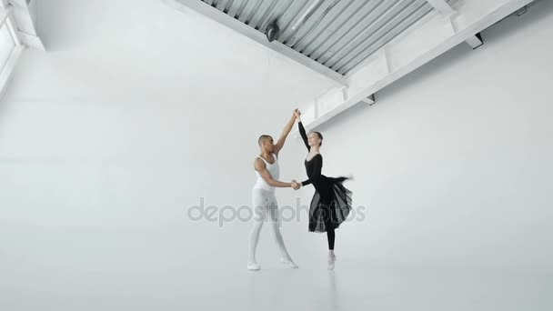 Meisje in het wit en een jongen in de zwarte dansers repeteren prestaties in een balletschool in de buurt van een groot raam close-up 20s 1080 p slow motion — Stockvideo