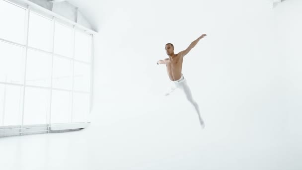 Bailarín de ballet con un torso desnudo y en leotardos blancos salta maravillosamente y muestra su estiramiento en cámara lenta 1080p 120fps . — Vídeo de stock