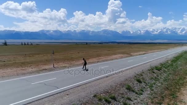 Homem monta em estrada reta em longboard ao pôr do sol tempo aéreo câmera lenta 4k — Vídeo de Stock