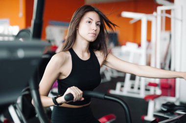 Spor takım elbiseli genç güzel beyaz kız fitness kulübünde sabit bir bisiklet üzerinde nişanlandı.