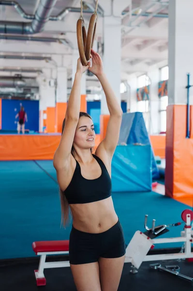 Young fit woman pulling up on gymnastic rings.