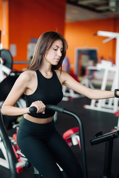 Kobieta 20s sobie smart oglądać, pracujących na rower treningowy — Zdjęcie stockowe