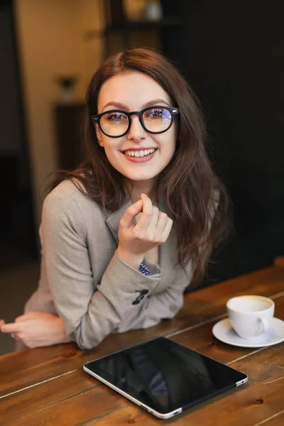 Портрет молодої дівчини, що п'є чай і використовує планшет, який дивиться з вікна кав'ярні — стокове фото